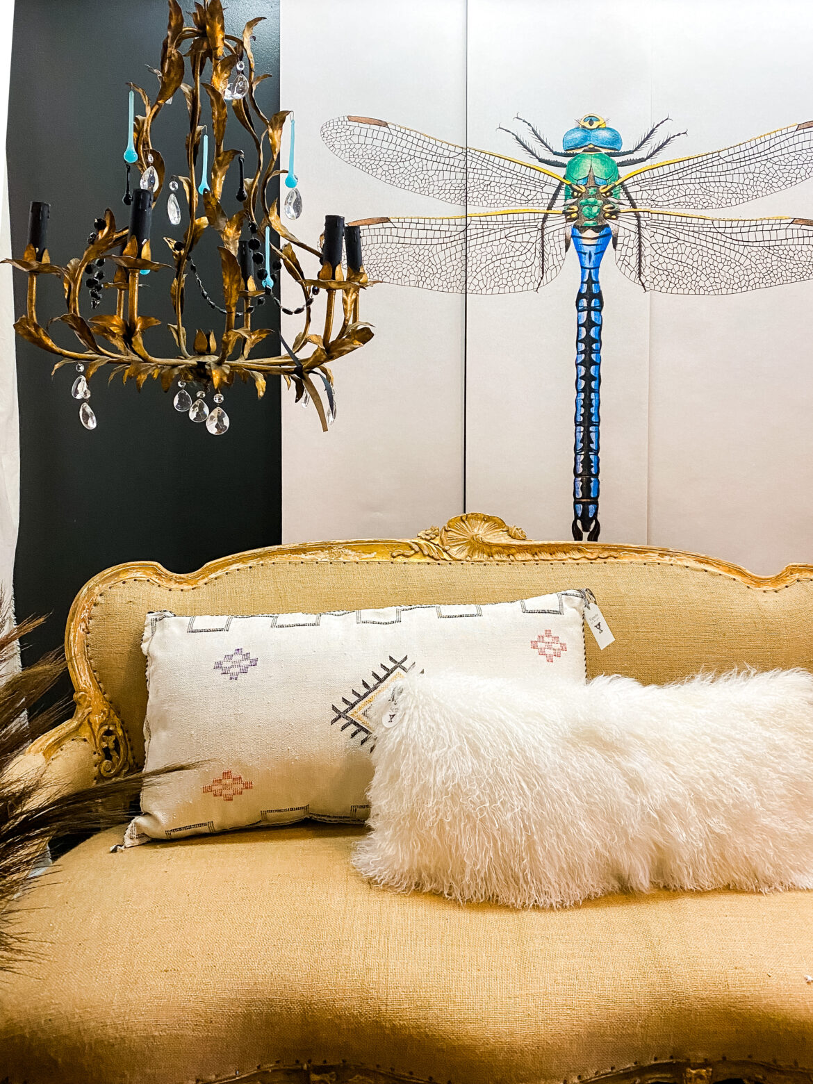 vintage cream couch in front of a vivid 5 foot tall dragonfly mural next to a vintage chandelier